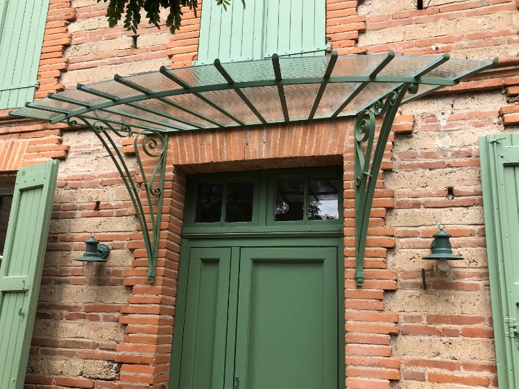 Pergola verte sur porte verte en brique