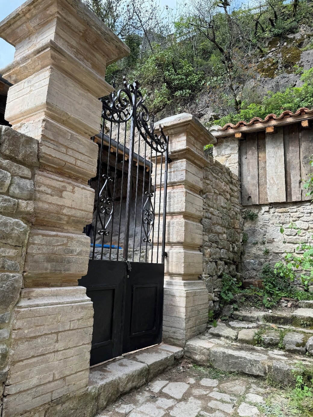 Porte en fer forgé entre des colonnes en pierre.