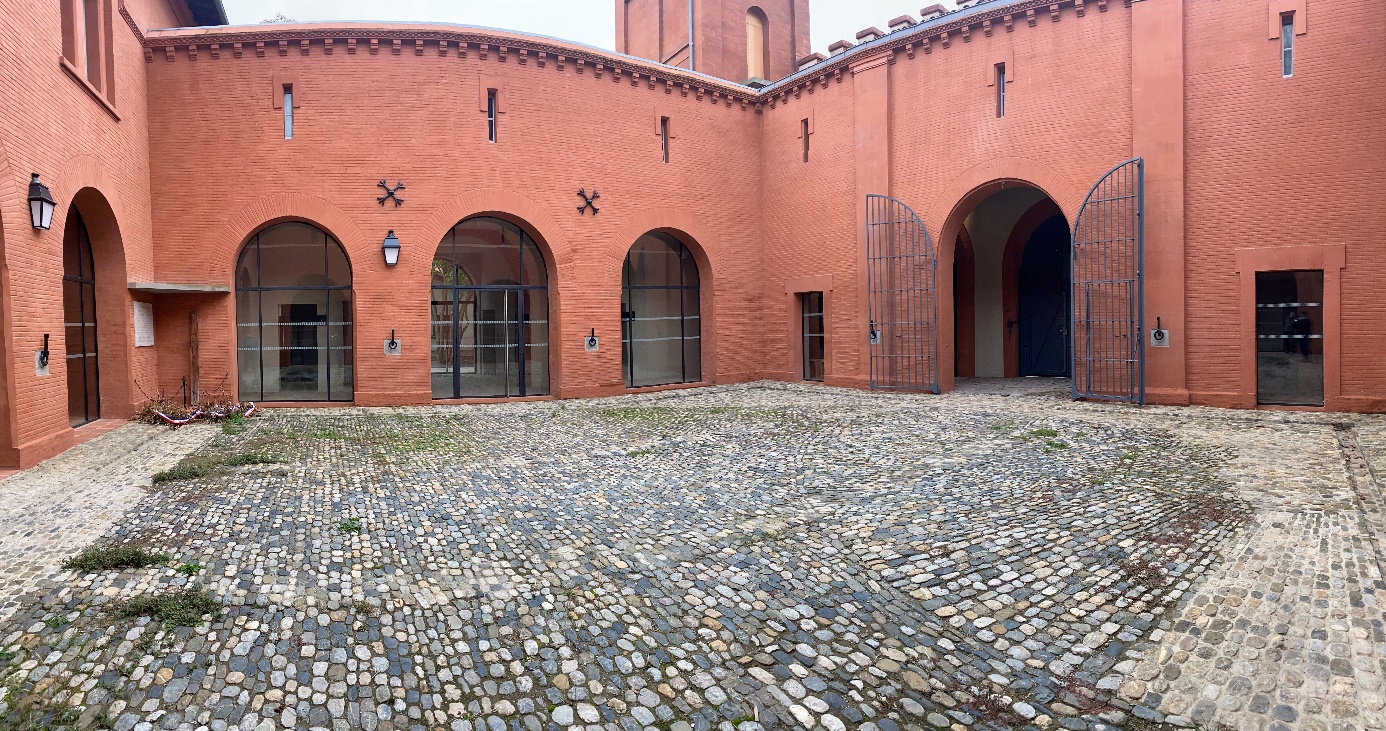 Cour intérieure en briques rouges avec pavage en pierre.