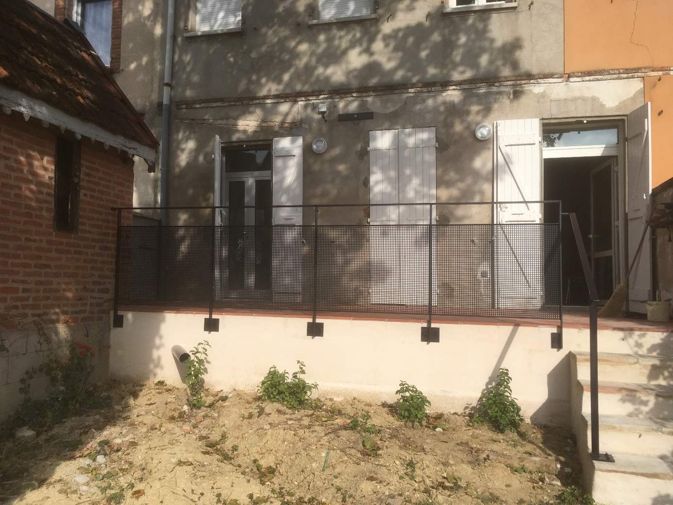 Balcon avec rambarde en métal, plantes en dessous