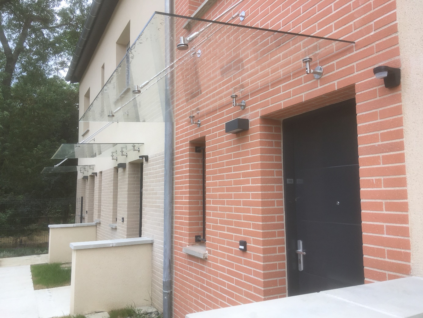 Bâtiment en briques avec auvents en verre et éclairage extérieur