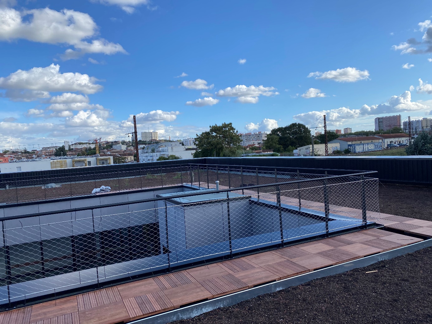 Terrasse en bois avec rambarde en fil de fer, vue urbaine