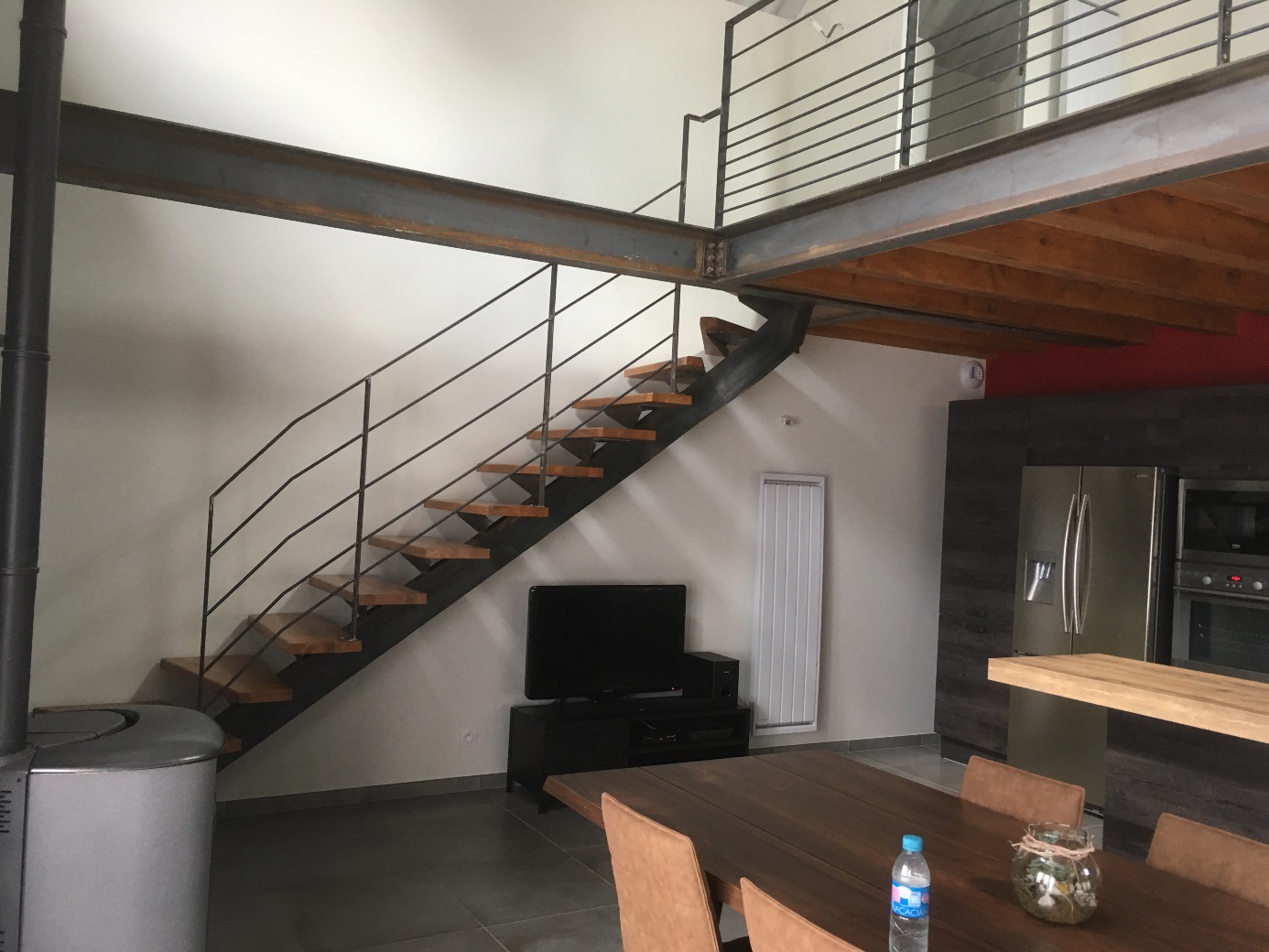 Escalier en métal et bois, table à manger, TV, réfrigérateur