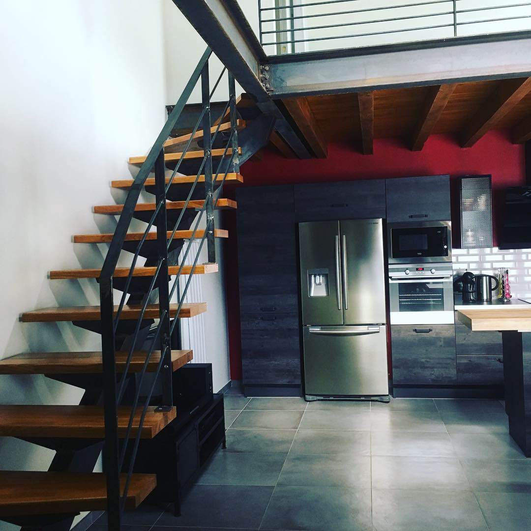 Escalier en métal et bois, cuisine moderne avec réfrigérateur en acier inoxydable