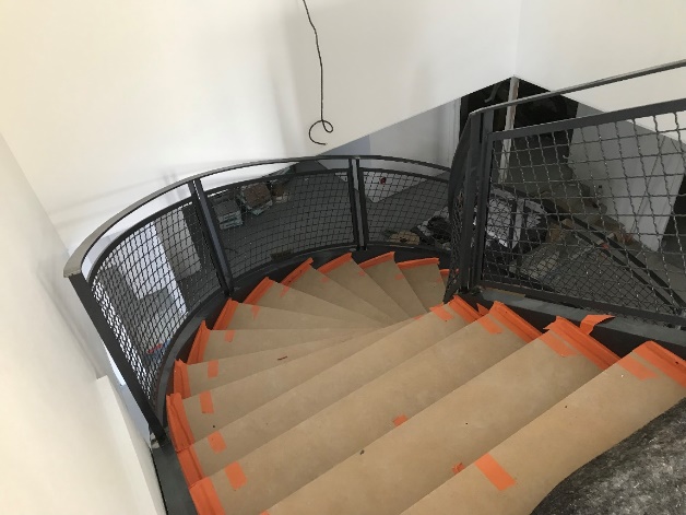 Escalier en colimaçon avec rambarde en métal et ruban orange