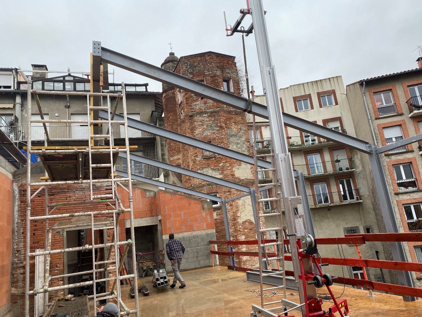 Construction en cours avec échafaudages et poutres métalliques.