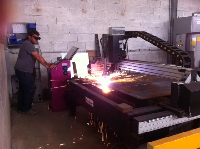 Homme utilisant une machine de découpe plasma dans un atelier.